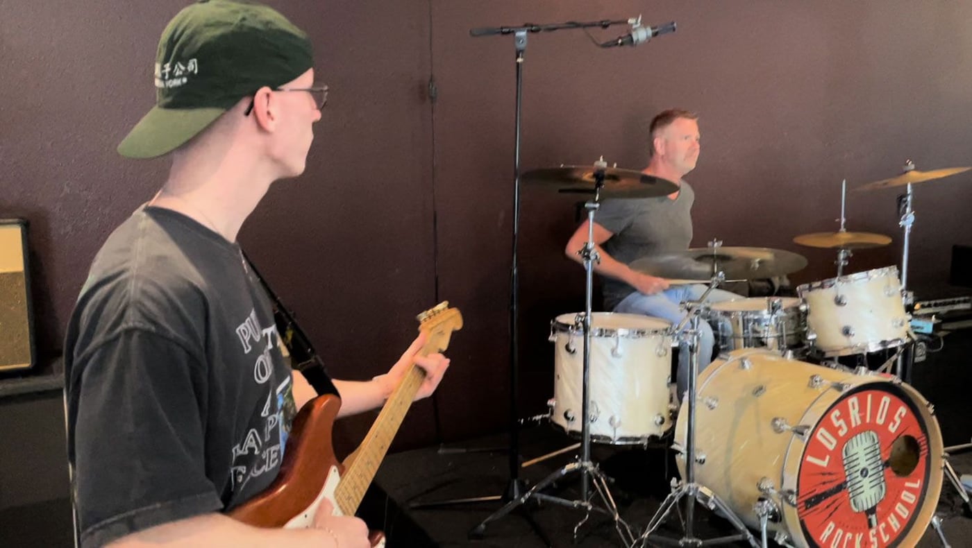A young bass player and a drummer working through a part together in a Los Rios rehearsal room